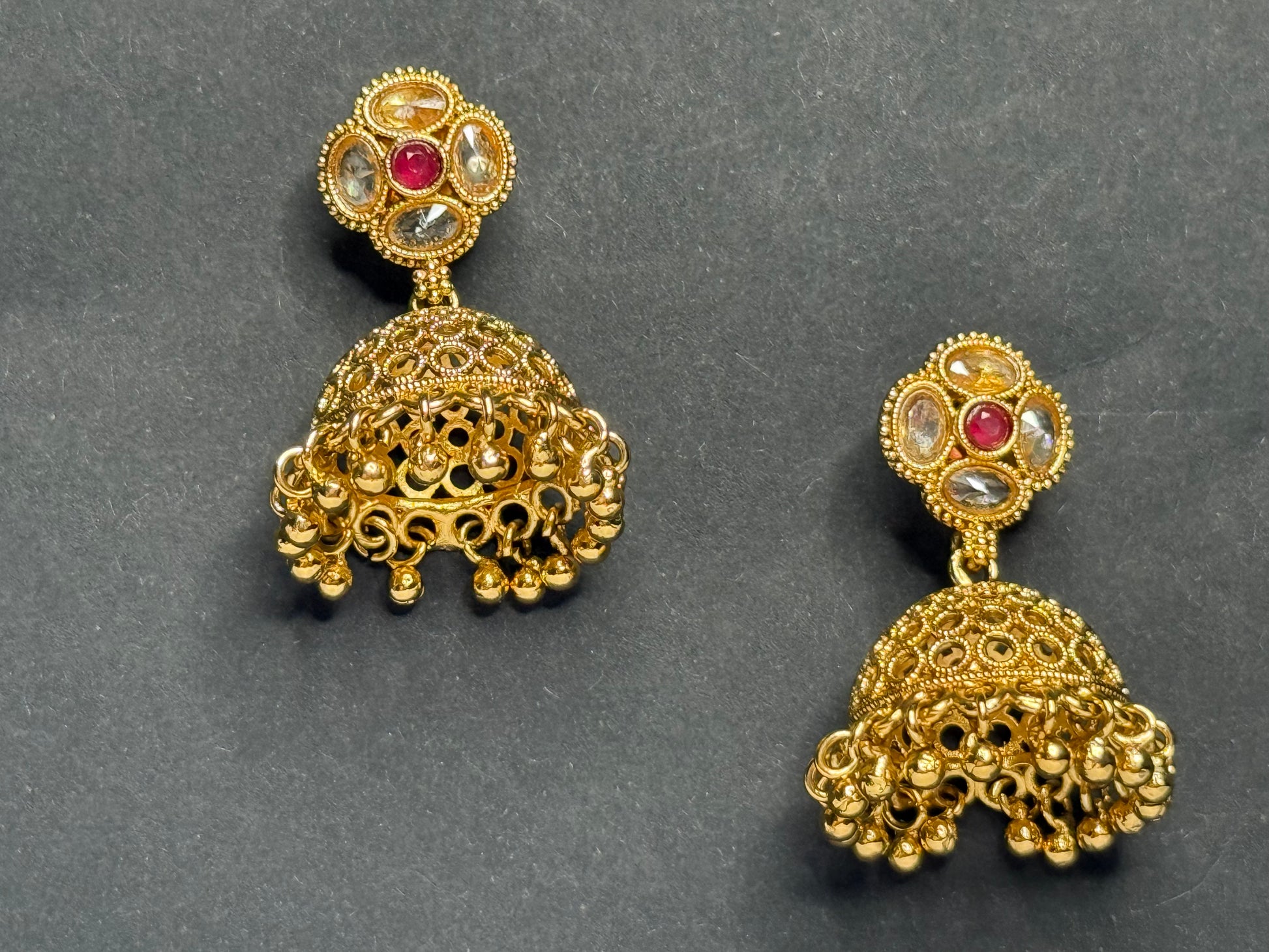 Gold earrings with intricate designs on a gray background